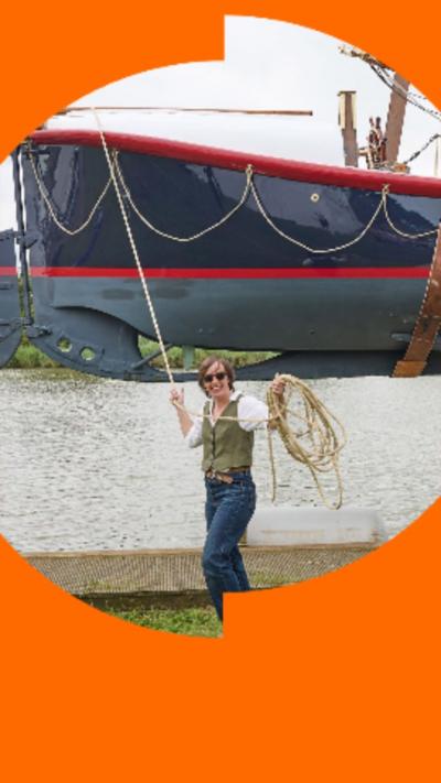A woman standing in front of a boat that's being held in the air