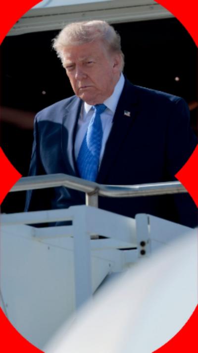 A man with short hair wearing a dark suit stands at the door of a plane